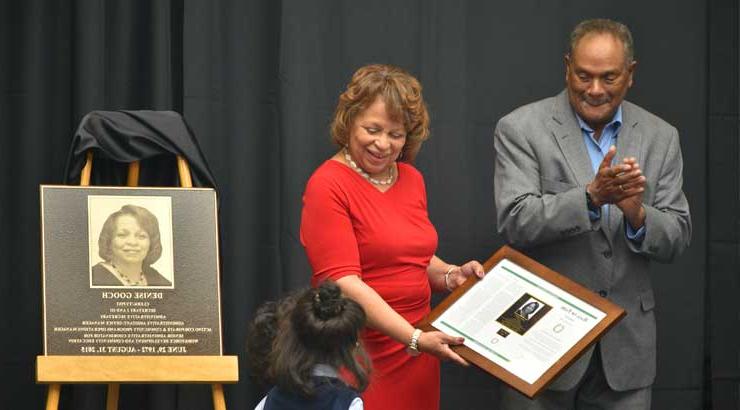 丹尼斯·古奇与她的丈夫和孙女一起拿着纪念纪念品领奖.